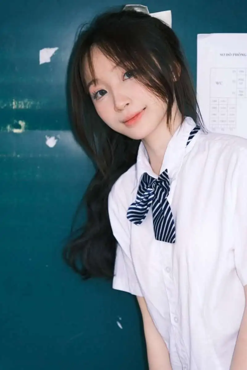 Gái học sinh mặc áo sơ mi trắng đứng trước bảng lớp học Gái học sinh mặc áo sơ mi trắng đứng trước bảng lớp học