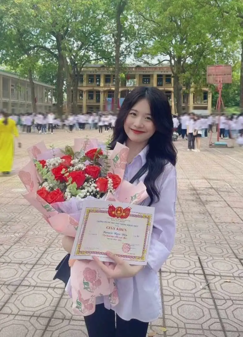 Gái học sinh mặc áo sơ mi cầm bó hoa và giấy khen Gái học sinh mặc áo sơ mi cầm bó hoa và giấy khen