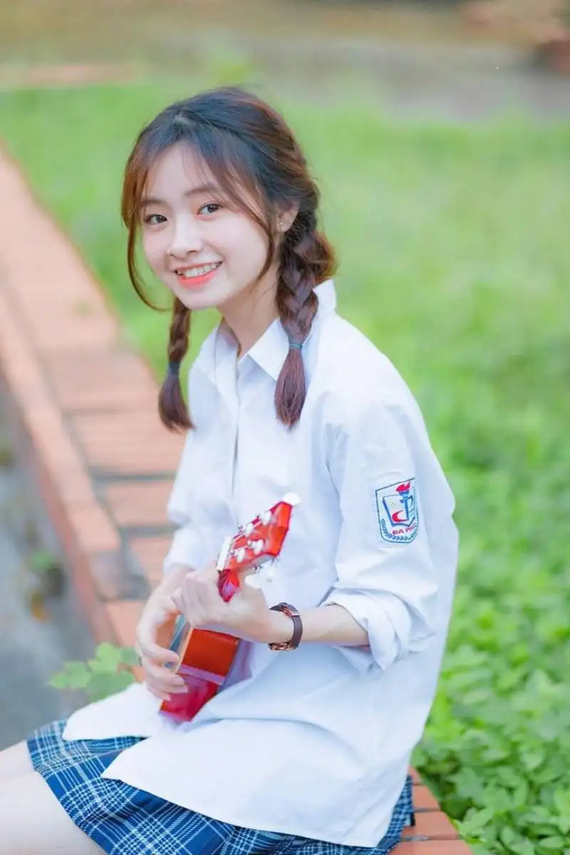 Gái học sinh mặc áo sơ mi ngồi đàn Ukulele Gái học sinh mặc áo sơ mi ngồi đàn Ukulele